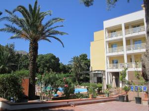a hotel with a palm tree and a swimming pool at Hotel Conchiglia d'Oro in Mondello