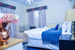 a hotel room with a bed and a table and chairs at Royal Highness Lux Guesthouse in Carletonville