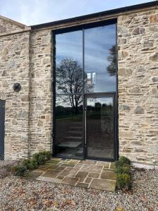 une porte en verre d'un bâtiment en pierre avec un arbre dans l'établissement The Hayloft, à Strabane