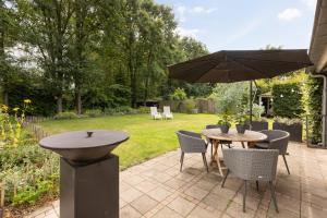 eine Terrasse mit einem Tisch, Stühlen und einem Sonnenschirm in der Unterkunft Onder het dak van Brabant in Mierlo