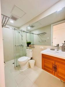 a bathroom with a toilet and a shower and a sink at 1 Bedroom - The Bali Getaway @ Azure North in San Fernando