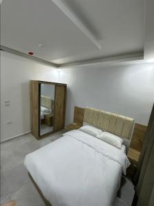 una camera da letto con un grande letto bianco e uno specchio di رويال جروب للشقق الفندقية a Irbid