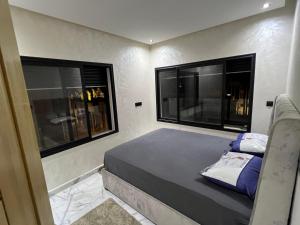 a small bedroom with two windows and a bed at Appartement Royal in El Jadida