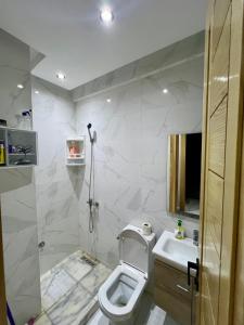 a white bathroom with a toilet and a sink at Appartement Royal in El Jadida
