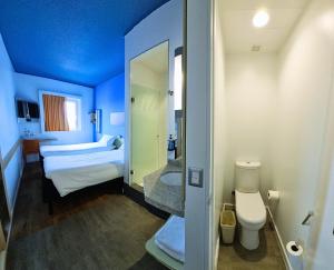 Habitación azul con cama y baño. en ibis budget Iquique, en Iquique