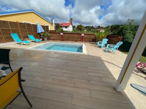 a patio with chairs and a swimming pool at Bungalow Candy avec piscine in Rivière-Salée