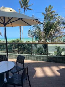 un patio con sedie, ombrellone e oceano di Coral Ritz - Flat beira mar (Condomínio Ritz Suites Home Service) a Maceió