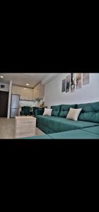 ein Wohnzimmer mit einer grünen Couch und einer Küche in der Unterkunft DM apartman in Ruma