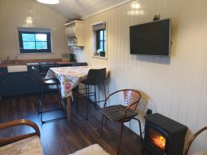 Zimmer mit einem Tisch, Stühlen und einem TV in der Unterkunft Rathgillen Cabin in Nobber