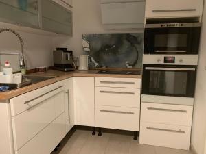 a kitchen with white cabinets and a stove top oven at Messe Apartment in Hannover