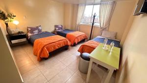 a room with three beds and a table and a window at Hostal la perla del sur in Quito
