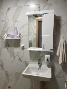 a white bathroom with a sink and a mirror at Golden Apartments Skopje in Skopje