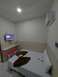 1 dormitorio con 1 cama blanca y TV de pantalla plana en Mini suíte Atitude Maragogi Centro en Maragogi