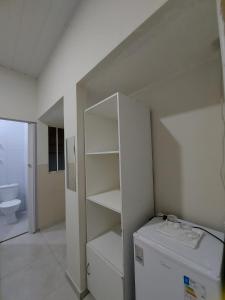 a white bathroom with a refrigerator and a toilet at Mini suíte Atitude Maragogi Centro in Maragogi