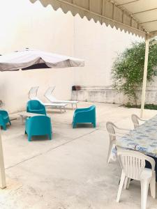 un patio con tavoli, sedie e ombrellone di Villino dei Dori, Marinella di Selinunte a Marinella di Selinunte