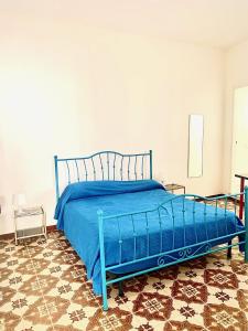 un letto blu in una camera da letto con pavimento piastrellato di Villino dei Dori, Marinella di Selinunte a Marinella di Selinunte