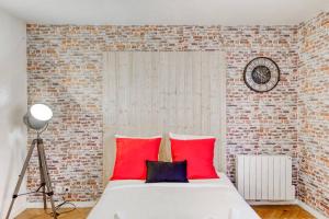 een slaapkamer met een bed met rode kussens en een bakstenen muur bij Magnifique studio la villette avec parking in Aubervilliers