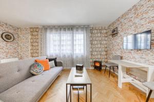 een woonkamer met een bank en een tafel bij Magnifique studio la villette avec parking in Aubervilliers
