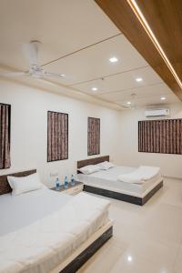 two beds in a room with white walls and windows at HOTEL AYODHYA in Virpur