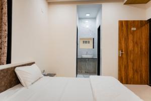 1 dormitorio con cama blanca y puerta de madera en HOTEL AYODHYA, en Virpur