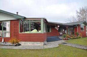 ein rotes Haus mit einem großen Fenster darauf in der Unterkunft Birchwood Cottages in Te Anau