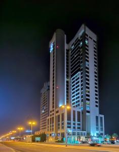 a tall building with lights on it at night at S Hotel Bahrain in Manama