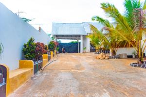 a dirt road in front of a building with palm trees at Bara Accommodations Paje in Paje