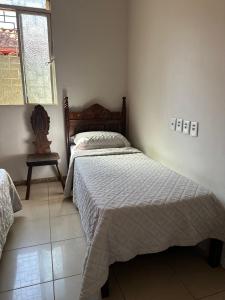 a bedroom with a bed and a chair and a window at Casa Grande Hospedagem in Brumadinho