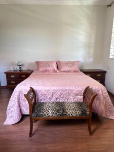 a bedroom with a bed with a pink comforter at Casa Grande Hospedagem in Brumadinho