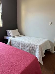 two beds in a room with pink and white sheets at Casa Grande Hospedagem in Brumadinho