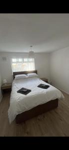 a bedroom with a bed with white sheets and a window at Entire 3 bedrooom holiday home in Liverpool