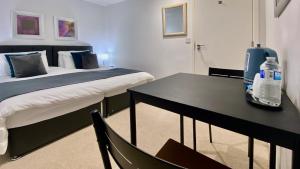 a bedroom with a bed and a table with two bottles of water at Maberic Housing II in Hounslow