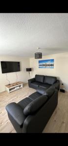 a living room with a black couch and a flat screen tv at Entire 3 bedrooom holiday home in Liverpool