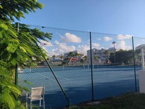 a tennis court with a chair on a tennis court at Saint Martin Villa on the beach in Baie Nettle