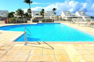 a swimming pool with blue water in front of houses at Saint Martin Villa on the beach in Baie Nettle