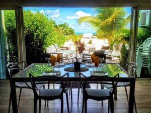 a dining room table with chairs and a view of the ocean at Saint Martin Villa on the beach in Baie Nettle