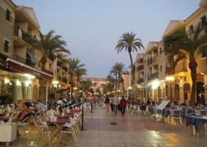 a city street with tables and chairs and palm trees at Villa Murcia Paradise in Los Alcázares