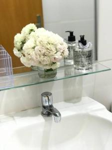 a glass shelf above a sink with a vase of flowers at Galpão Rústico no Vale dos Vinhedos in Bento Gonçalves