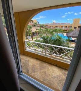 uma janela com vista para a piscina a partir de um resort em Apto 2quartos Buzios/Vista p/mar/Piscina em Nísia Floresta