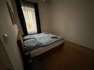 - un petit lit dans une chambre avec fenêtre dans l'établissement Apartmán Raisova 1180, à Karlovy Vary