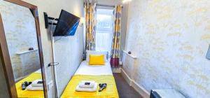 a small room with a yellow bed and a mirror at mySTAYINN Kinloch 7 Bedroom House in Inverness