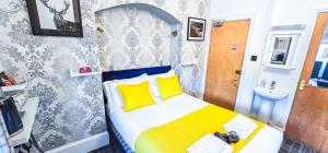 a bedroom with a bed with yellow pillows and a sink at mySTAYINN Kinloch 7 Bedroom House in Inverness