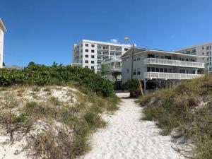 un chemin de sable menant à un bâtiment sur une plage dans l'établissement Seaside Cottage, à Clearwater Beach