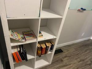 a white book shelf with books on it at Sleek 3 bedroom home close to Exchange W parking in Winnipeg