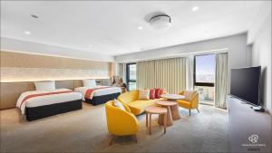 a hotel room with two beds and a flat screen tv at Daiwa Roynet Hotel NAHA-OMOROMACHI PREMIER in Naha