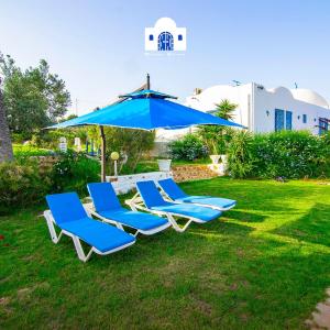 a group of blue lounge chairs and an umbrella at Maison eirene in Hammamet