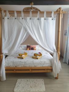 ein Bett mit Baldachin und zwei Handtüchern darauf in der Unterkunft Le Mouton Gras in Aumale