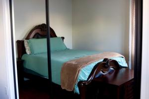 a bedroom with a green bed with a mirror at Cozy East Haven Apartment - Walk to Beach! in East Haven
