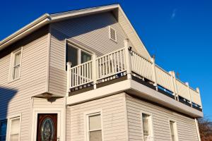 a white house with a balcony on top of it at Cozy East Haven Apartment - Walk to Beach! in East Haven