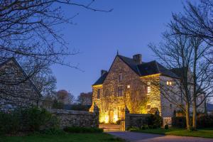 an old stone house with lights on it at night at Gîte des Fougères in Cherbourg en Cotentin